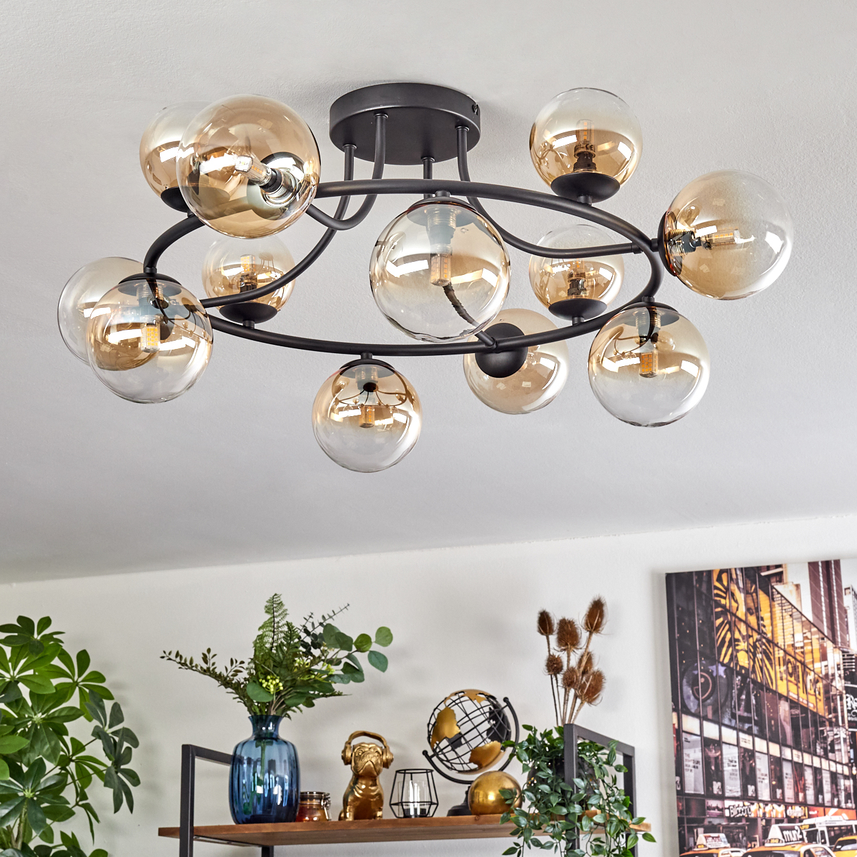 Eine moderne Deckenleuchte mit mehreren kugelförmigen Glasschirmen. Darunter ein Regal mit Dekorationsartikeln, darunter ein Globus und eine Vase.