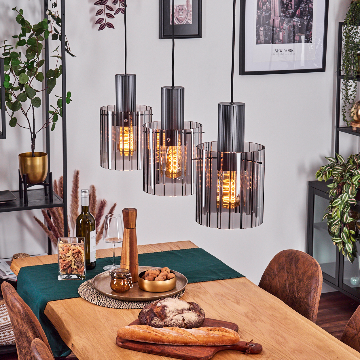 Esstisch mit Hängelampen. Essen und Getränke stehen auf dem Tisch. Pflanzen und Dekorationen im Hintergrund.
