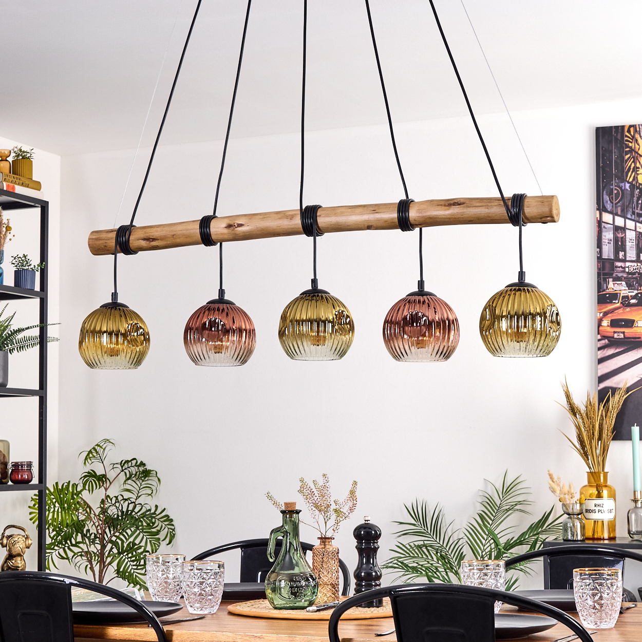 Esszimmer mit Holztisch, schwarzen Stühlen und einer Hängeleuchte mit fünf Glaslampen.
