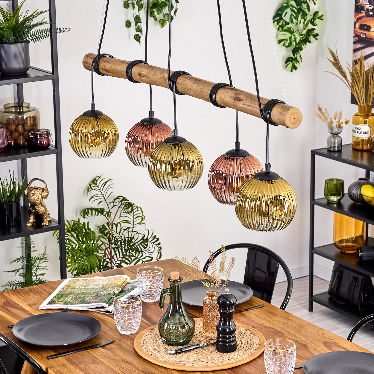 Esszimmer mit Holztisch, dekorativer Beleuchtung und Tischdeko. Pflanzen und Regale mit Dekoration sind im Hintergrund sichtbar.