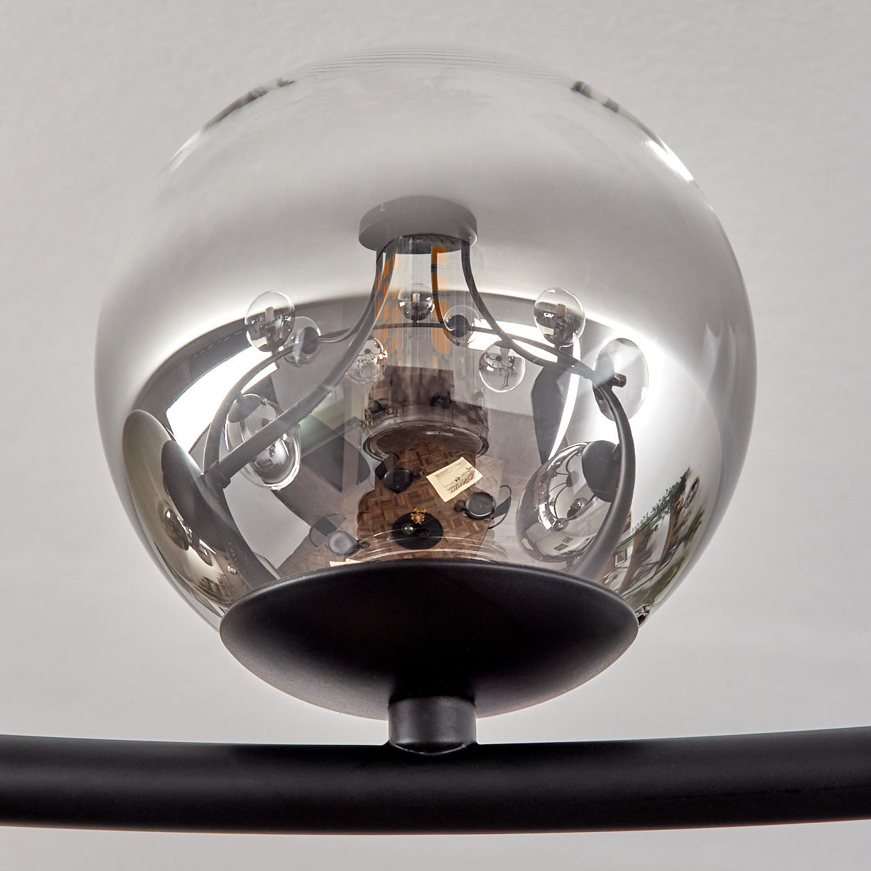 Eine moderne, kugelförmige Hängeleuchte mit rauchfarbenem Glasschirm. Sie hat kleine, klare Glaskugeln und einen schwarzen Metallrahmen.