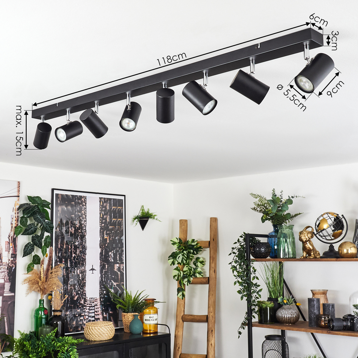 Schwarze Deckenstrahler, 118 cm lang, abgewinkelt. Darunter ein Raum mit Pflanzen, einer Leiter, einem schwarzen Schrank und einem Stadtbild.