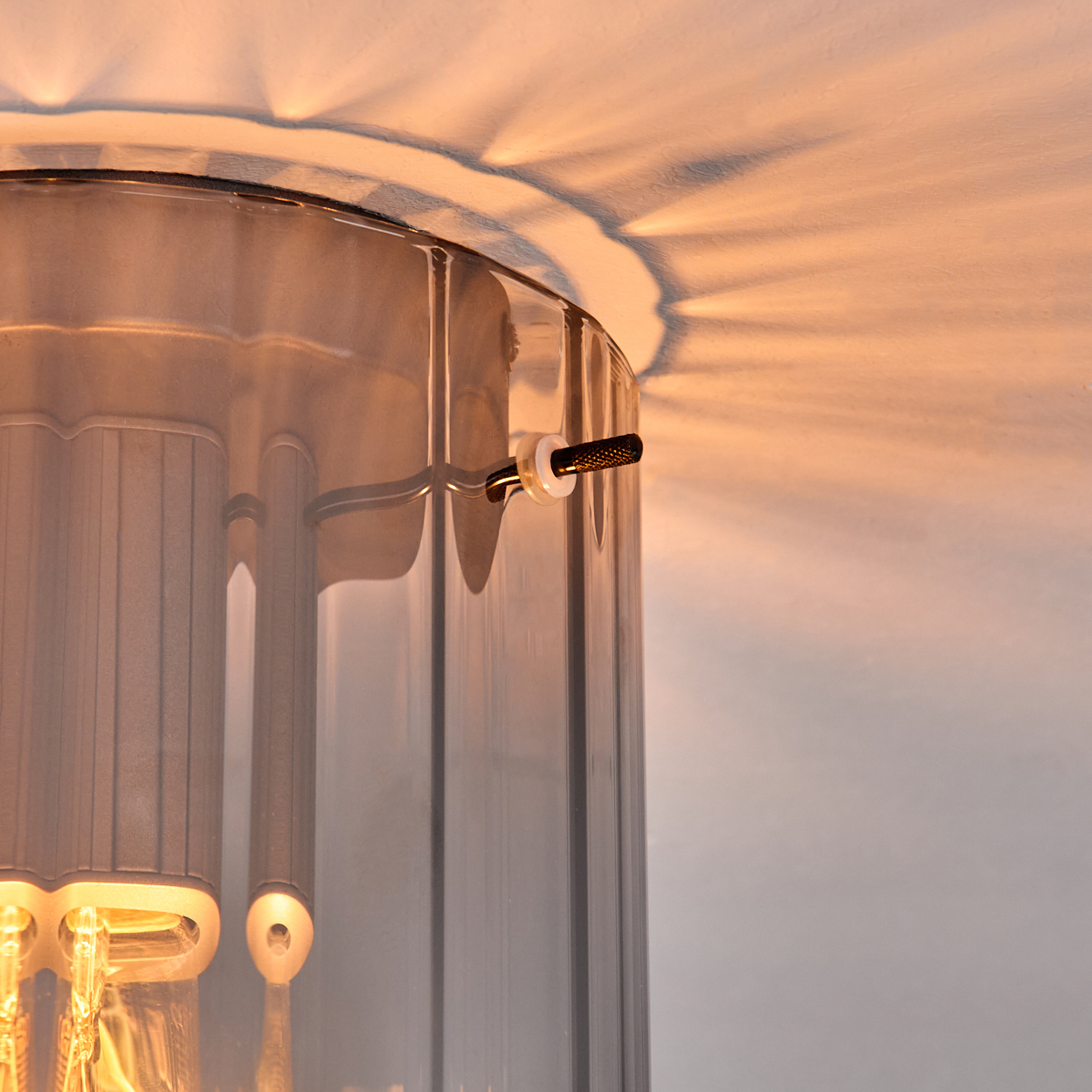 Nahaufnahme einer Glaslampe mit Lichtstreifen an der Decke. Ein schwarzer Schalter ist sichtbar.