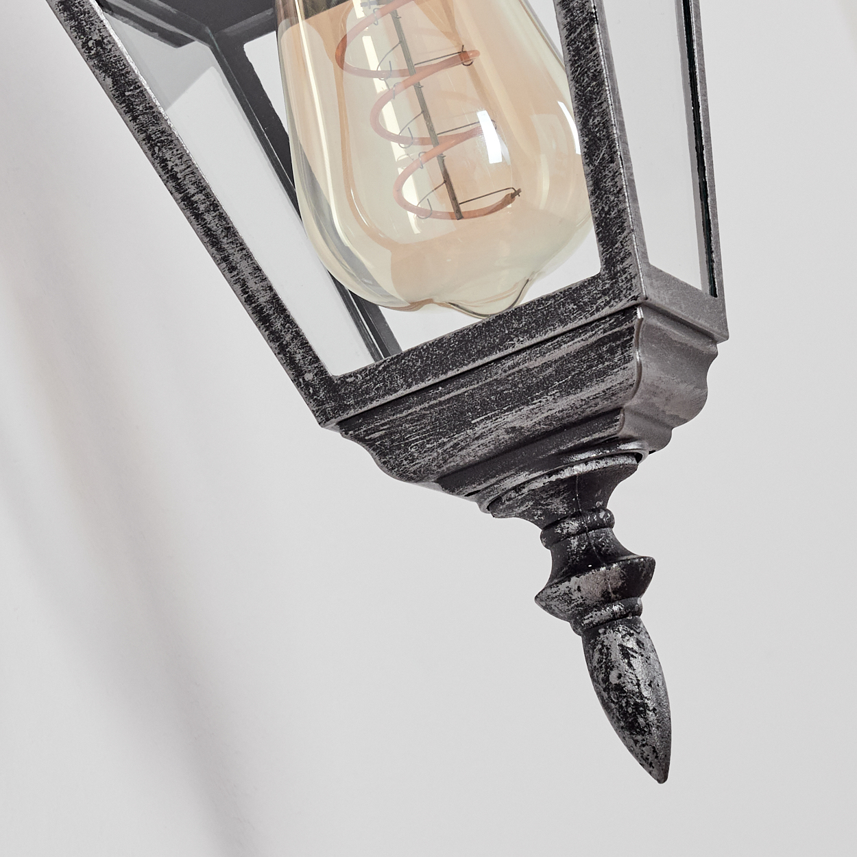 Nahaufnahme einer dekorativen Lampe mit sichtbarer Glühbirne. Die Lampe ist schwarz und hat unten einen Stachel.