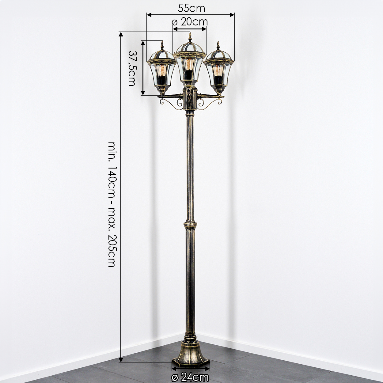 Eine dekorative Außenlampe mit drei glaseingeschlossenen Lichtern. Sie hat eine Bronzefarbe und steht in einer Ecke an weißen Wänden.