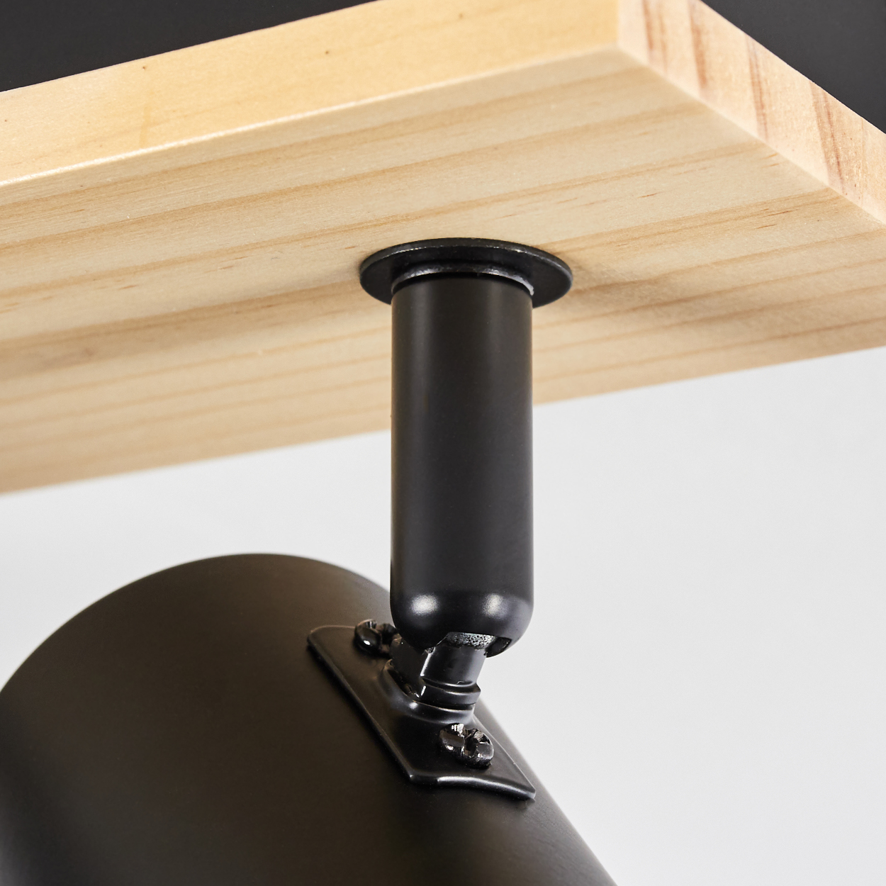 Nahaufnahme einer schwarzen Lampenhalterung, die an einer Holzplanke befestigt ist. Die Lampe hat eine zylindrische Form.