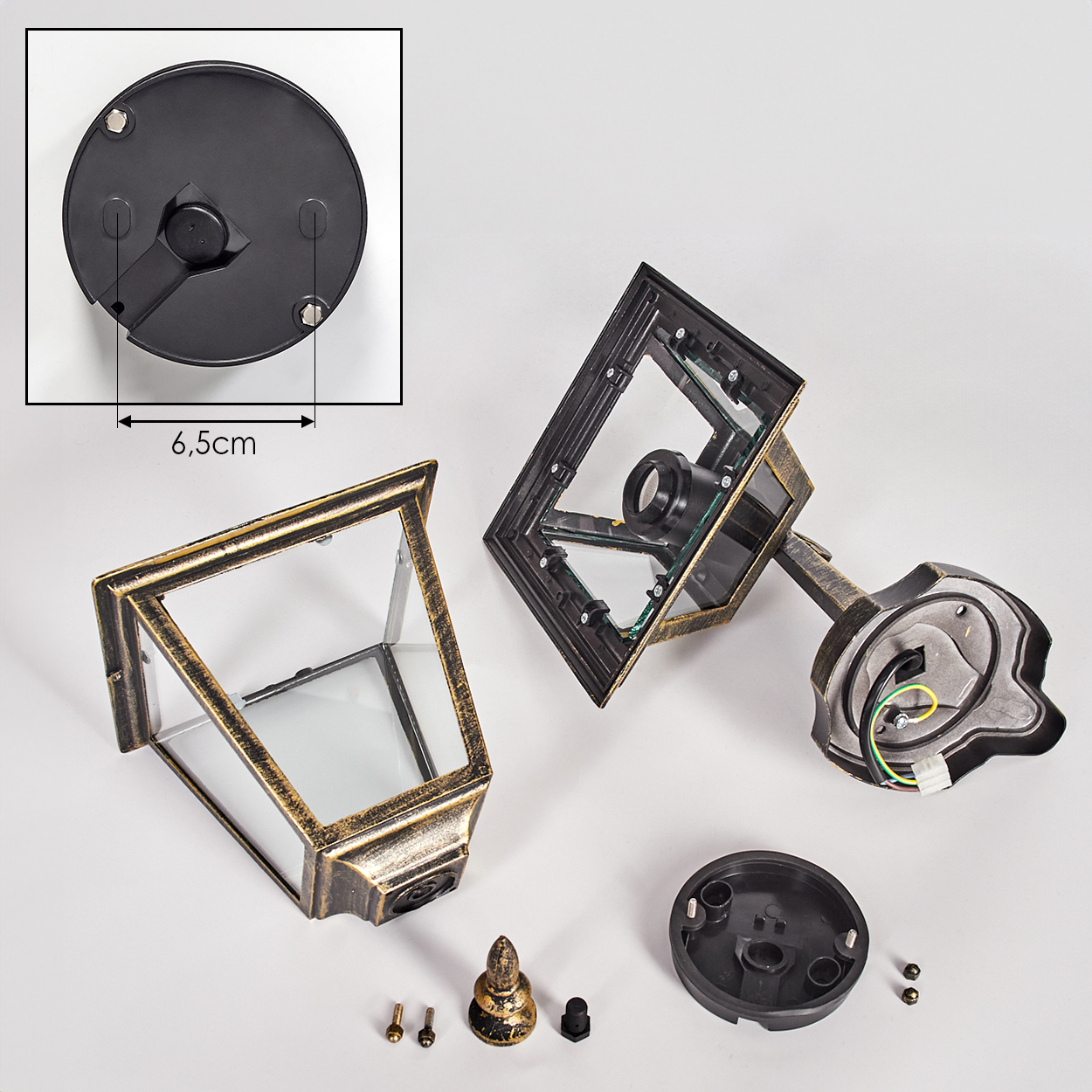 Zerlegte Teile einer Außenlampe auf weißem Untergrund. Enthält Lampenrahmen, Sockel, Schrauben und andere Komponenten.