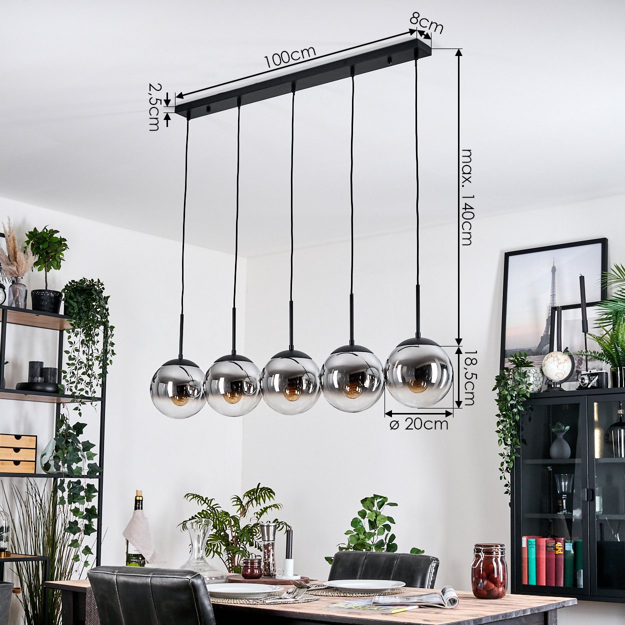 Ein modernes Esszimmer mit einem schwarzen Kronleuchter mit fünf kugelförmigen Lichtern. Ein Tisch ist mit Pflanzen und einem gerahmten Eiffelturm-Bild gedeckt.