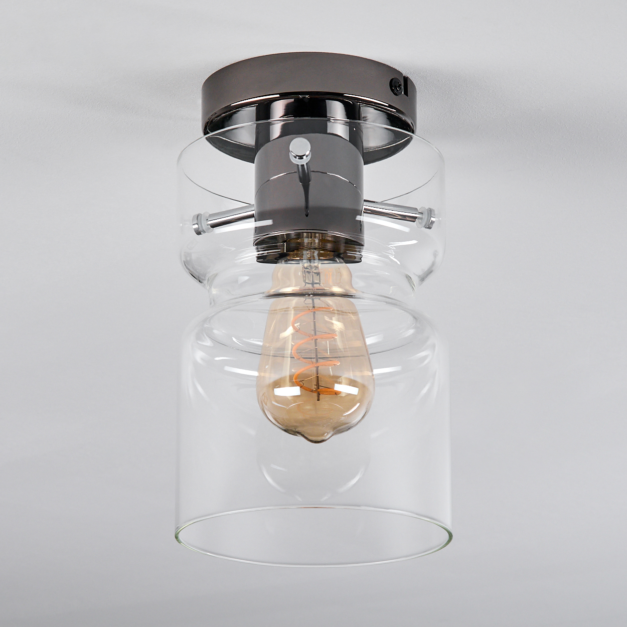 Moderne Deckenleuchte mit Glasschirm und sichtbarer Edison-Glühbirne. Die Leuchte hat eine dunkle Metallausführung.