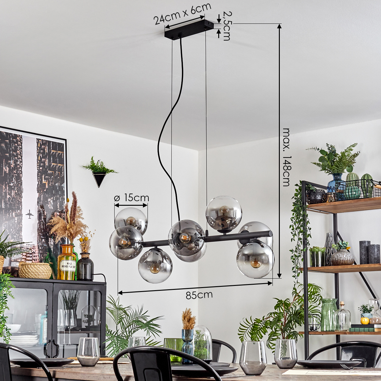 Eine moderne Pendelleuchte mit Glaskugeln hängt über einem Esstisch. Die Szene umfasst Pflanzen, einen Schrank und ein Holzregal mit Dekoration.