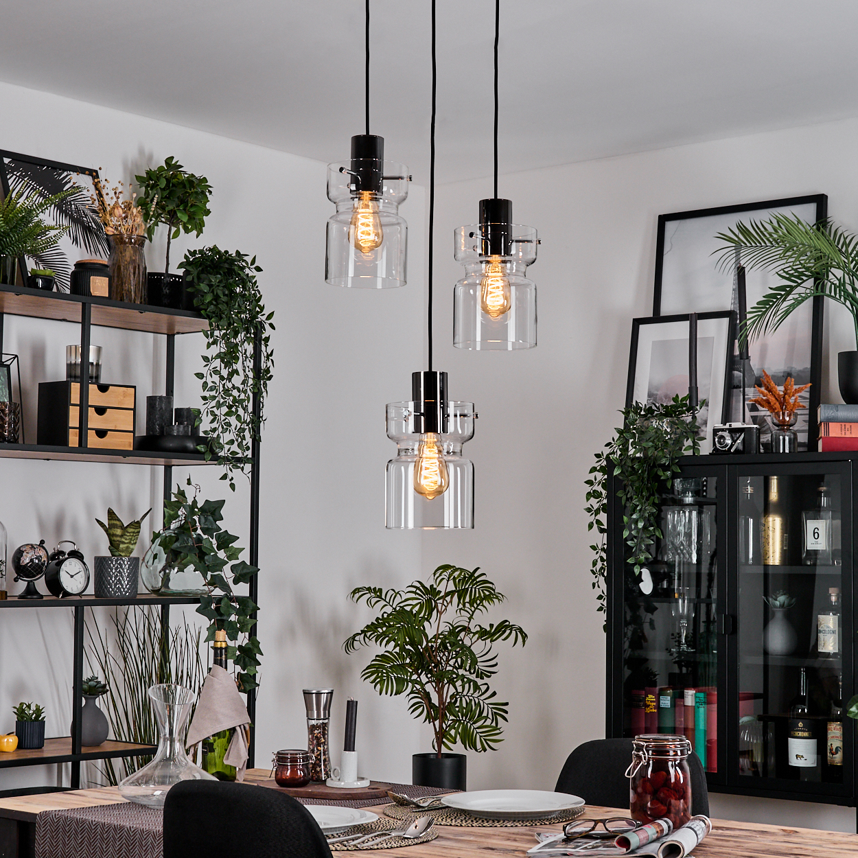 Esszimmer mit Hängelampen, Regalen mit Dekorationen, einem gedeckten Tisch und einem Schrank mit Flaschen und Dekorationen.