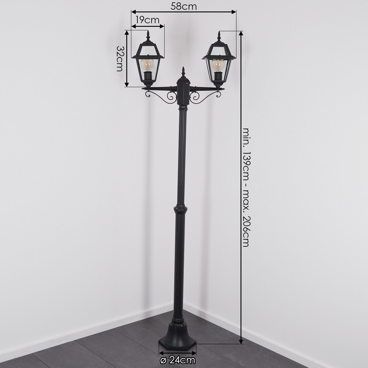 Schwarze Außenlaterne mit zwei Laternen. Abmessungen sind angegeben. Sie steht vor einer weißen Wand und einem dunklen Boden.