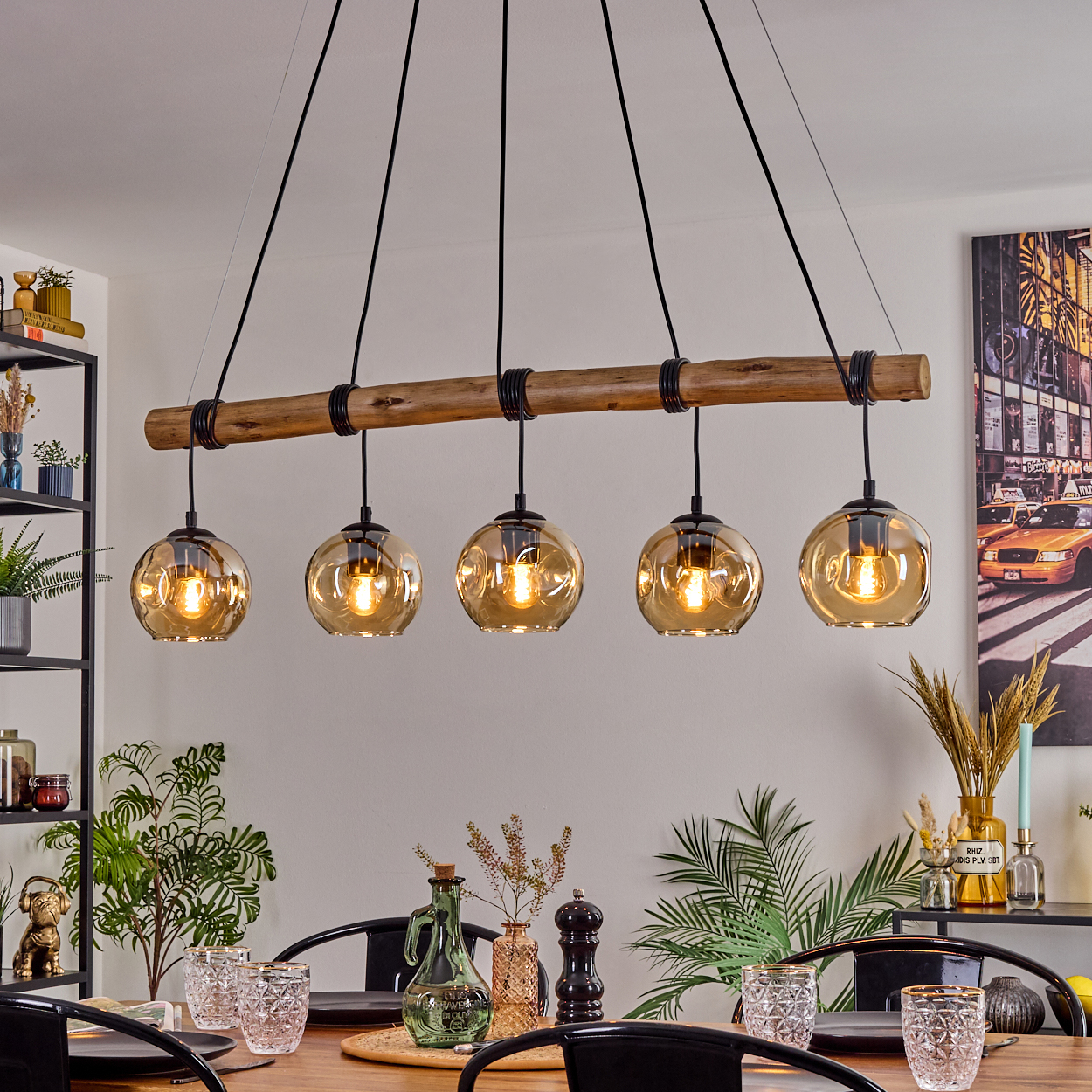 Ein Esszimmer mit Holztisch, schwarzen Stühlen und einer Hängelampe mit fünf Glaskugelleuchten.