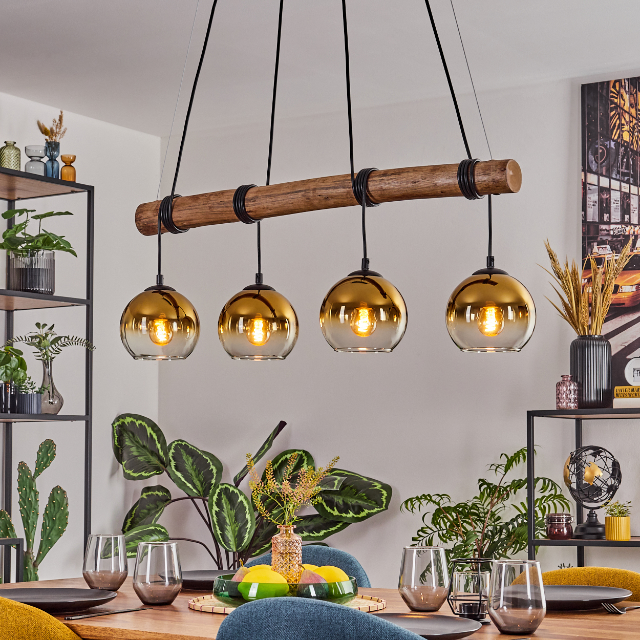 Esszimmer mit Holztisch. Oben hängen Lampen mit goldfarbenen Glasschirmen. Pflanzen und Dekoration sind vorhanden.