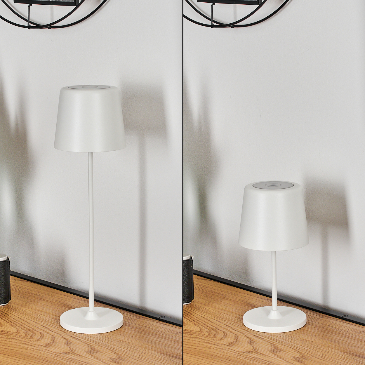 Zwei weiße Tischlampen auf einer Holzoberfläche vor einer weißen Wand. Eine Lampe ist größer. Links ein schwarzes Objekt.