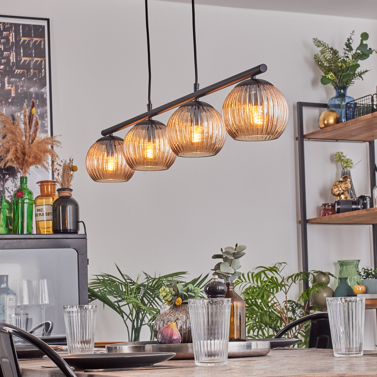 Esszimmer mit Holztisch, Gläsern und einer Hängelampe mit vier Glaskugeln.