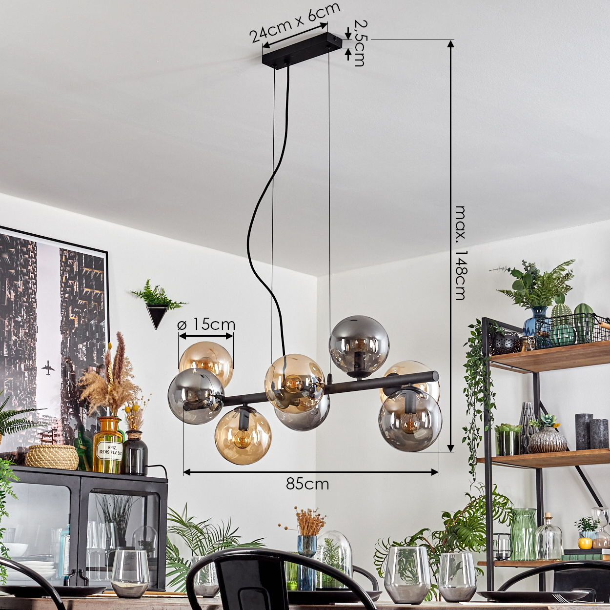 Eine moderne Hängelampe mit kugelförmigen Lampen hängt über einem Esstisch. Abmessungen sind angegeben. Der Hintergrund hat Regale, Pflanzen und Kunst.