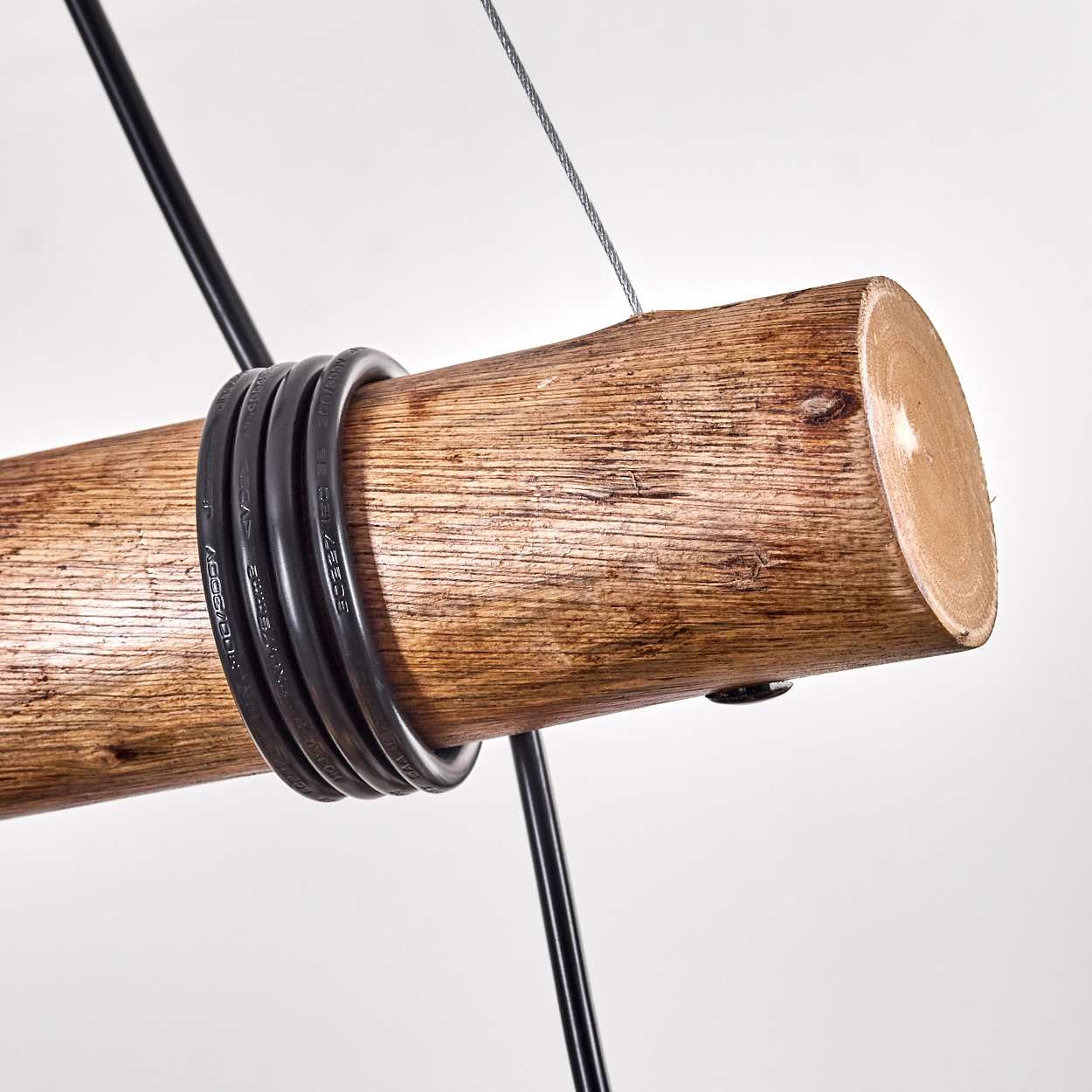 Ein Holzstamm mit schwarzen Kabeln. Ein silbernes Kabel und schwarzer Draht sind befestigt, mit weißem Hintergrund.