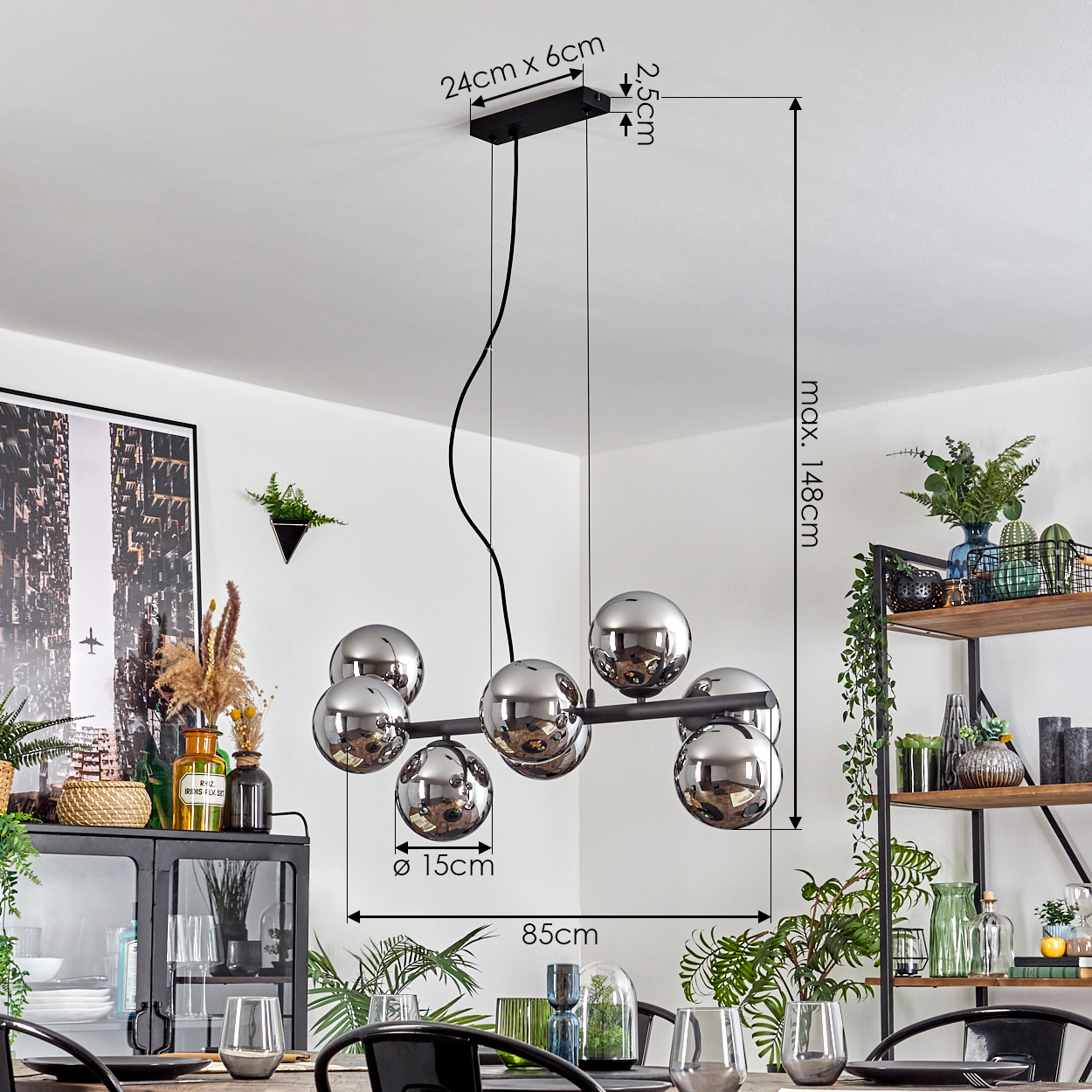 Ein modernes Esszimmer mit einem schwarzen Kronleuchter mit Glaskugeln. Es gibt einen gedeckten Tisch, ein schwarzes Regal mit Pflanzen und Dekorationen.