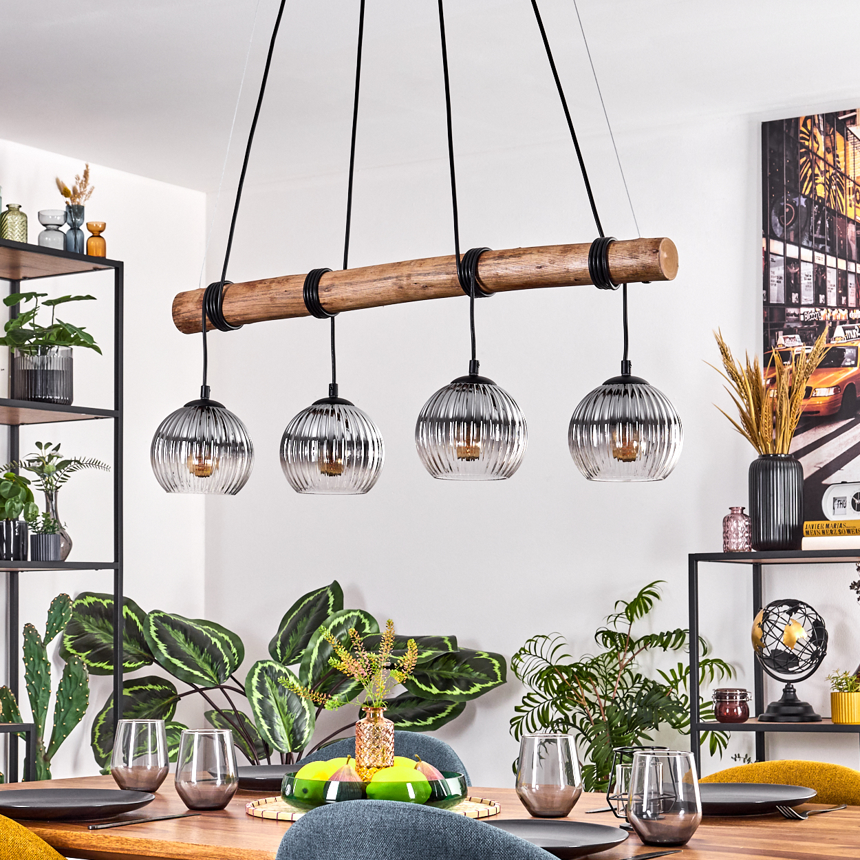 Ein Esszimmer mit Holztisch, Hängelampen, Pflanzen und einem Stadtbildgemälde im Hintergrund.