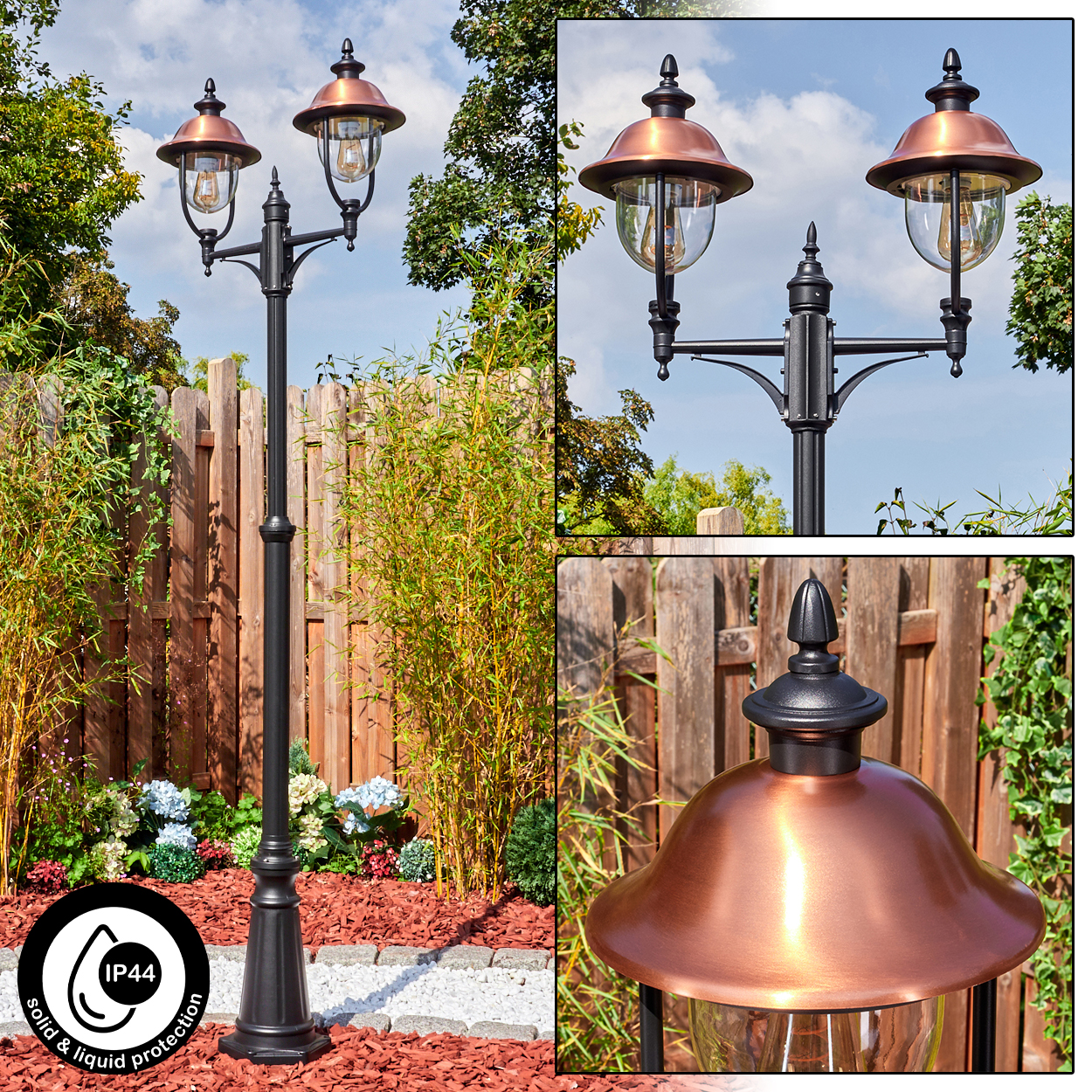 Eine schwarze Außenlampe mit kupferfarbenen Schirmen steht in einem Garten mit Holzzaun und Bambuspflanzen.