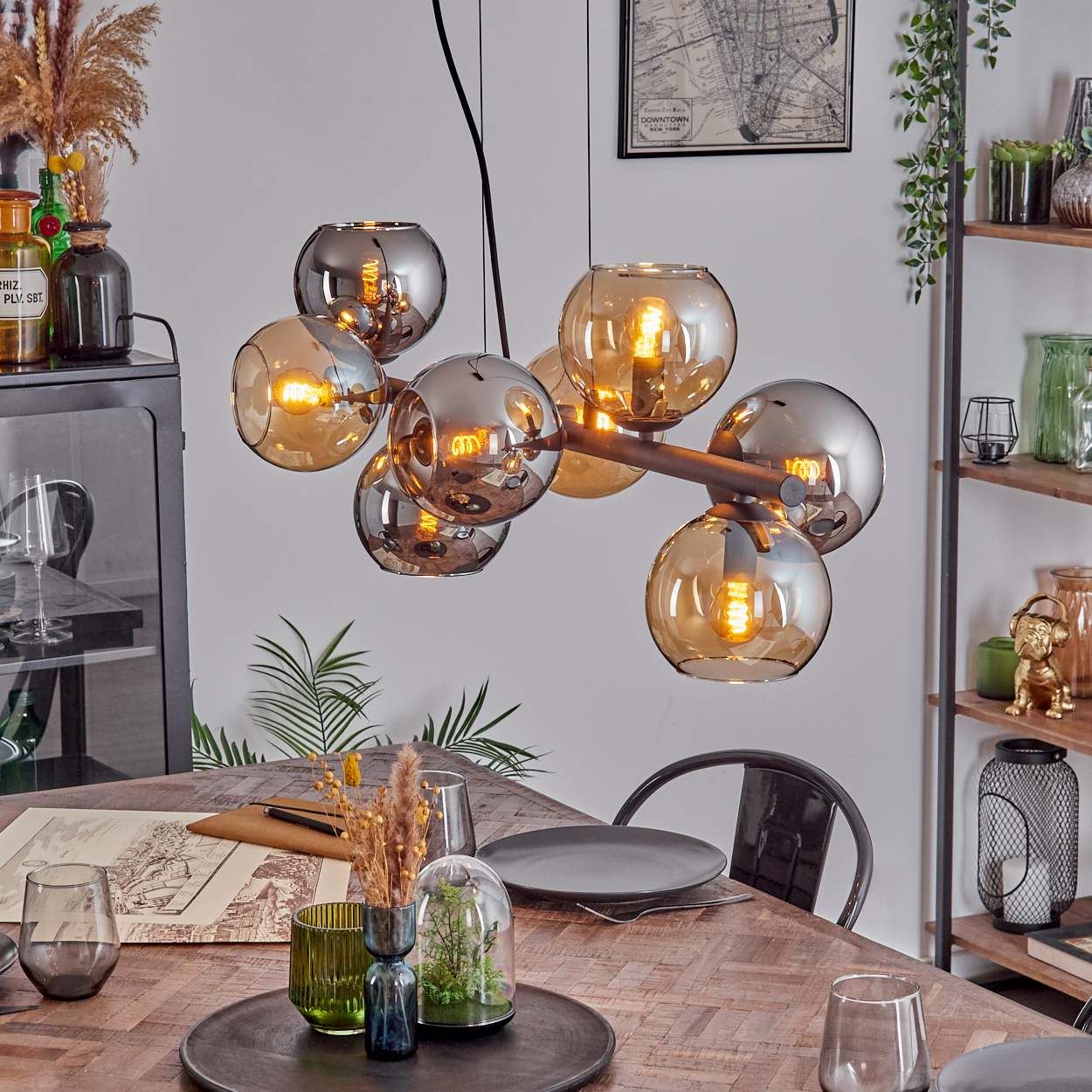 Esszimmer mit Holztisch, Kronleuchter mit Glaskugeln und Dekoration. Eine Karte hängt an der Wand.