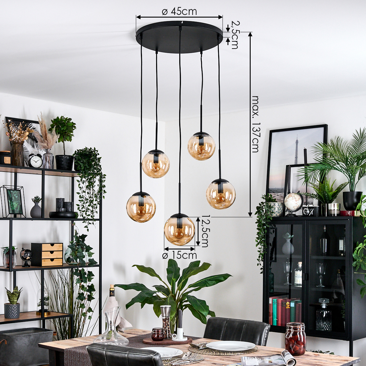 Esszimmer mit schwarzem Kronleuchter mit fünf bernsteinfarbenen Glaskugeln. Verschiedene Pflanzen und Möbel im Hintergrund.