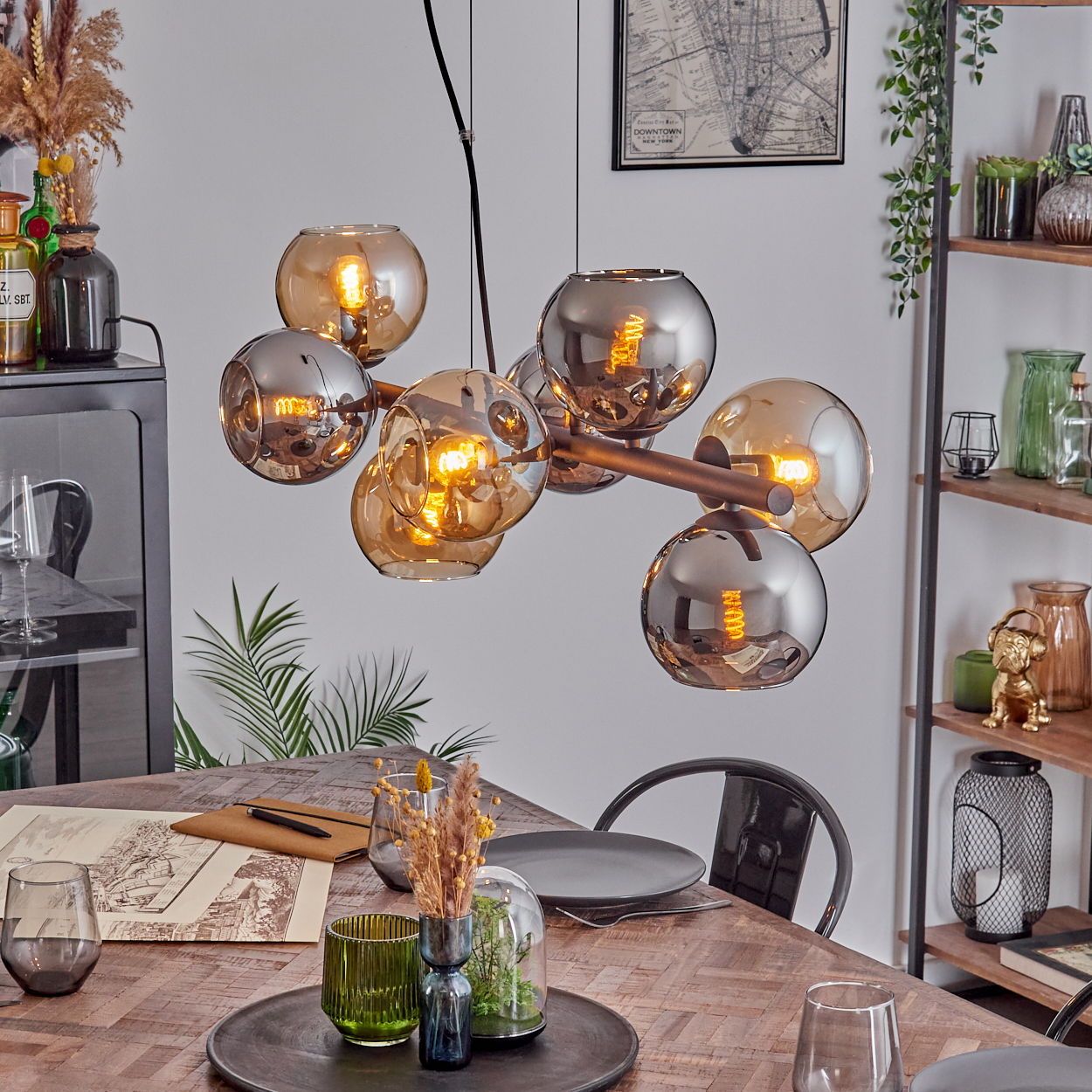 Ein modernes Esszimmer mit Holztisch, Kronleuchter und Dekoration, darunter Pflanzen und Ornamente.