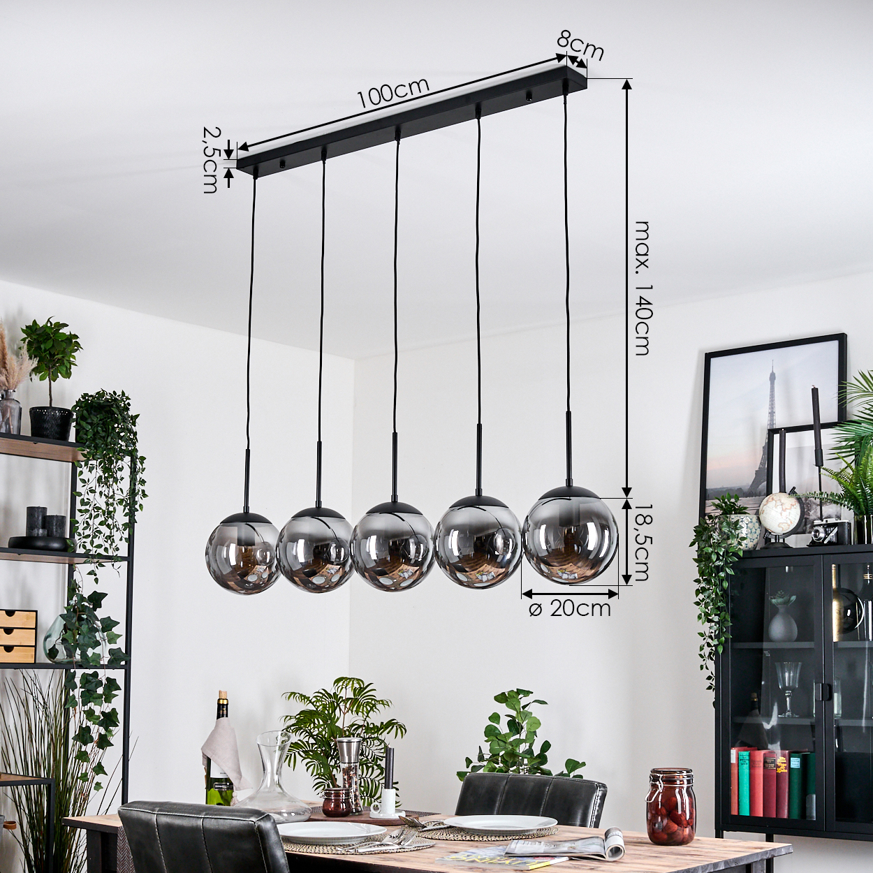 Esszimmer mit schwarzem Kronleuchter mit fünf kugelförmigen Lichtern. Im Hintergrund stehen Tisch und Stühle sowie Pflanzen.