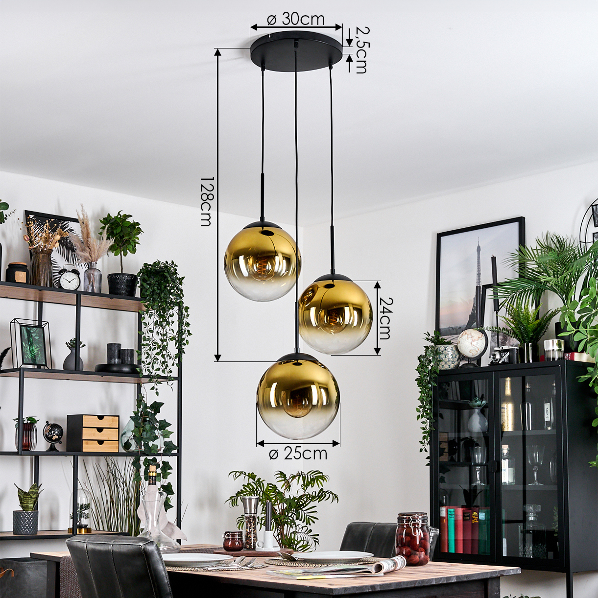 Drei goldene Pendelleuchten hängen über einem Esstisch. Pflanzen und Dekorationen füllen den Hintergrund. Maße sind enthalten.