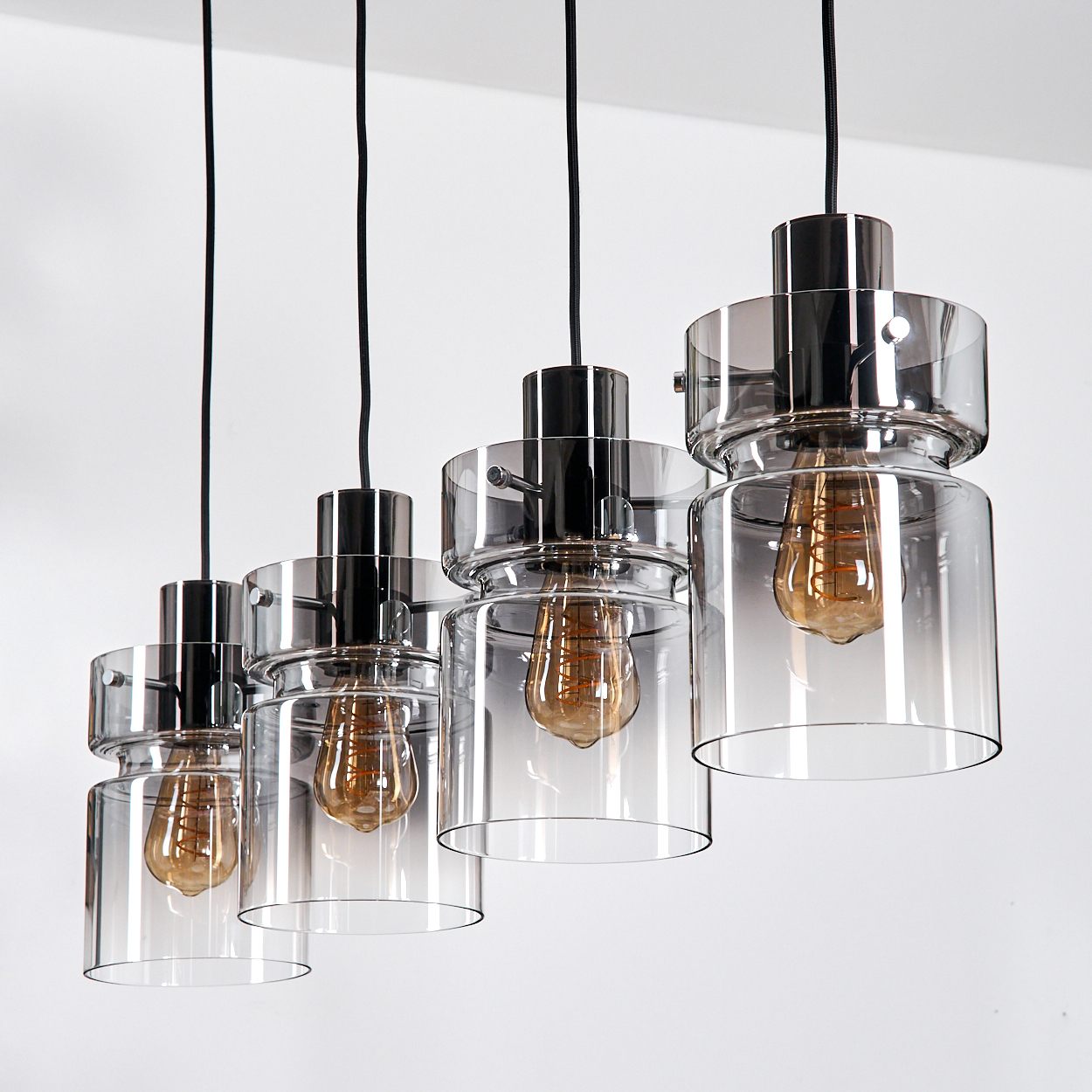 Fünf hängende Pendelleuchten mit Glasschirmen und Edison-Glühbirnen vor weißem Hintergrund.