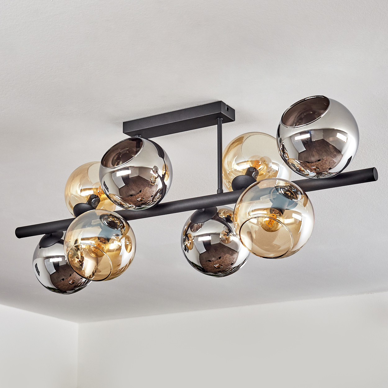 Moderne Deckenleuchte mit kugelförmigen Glasschirmen in Silber und Amber, montiert auf einem schwarzen Metallrahmen.