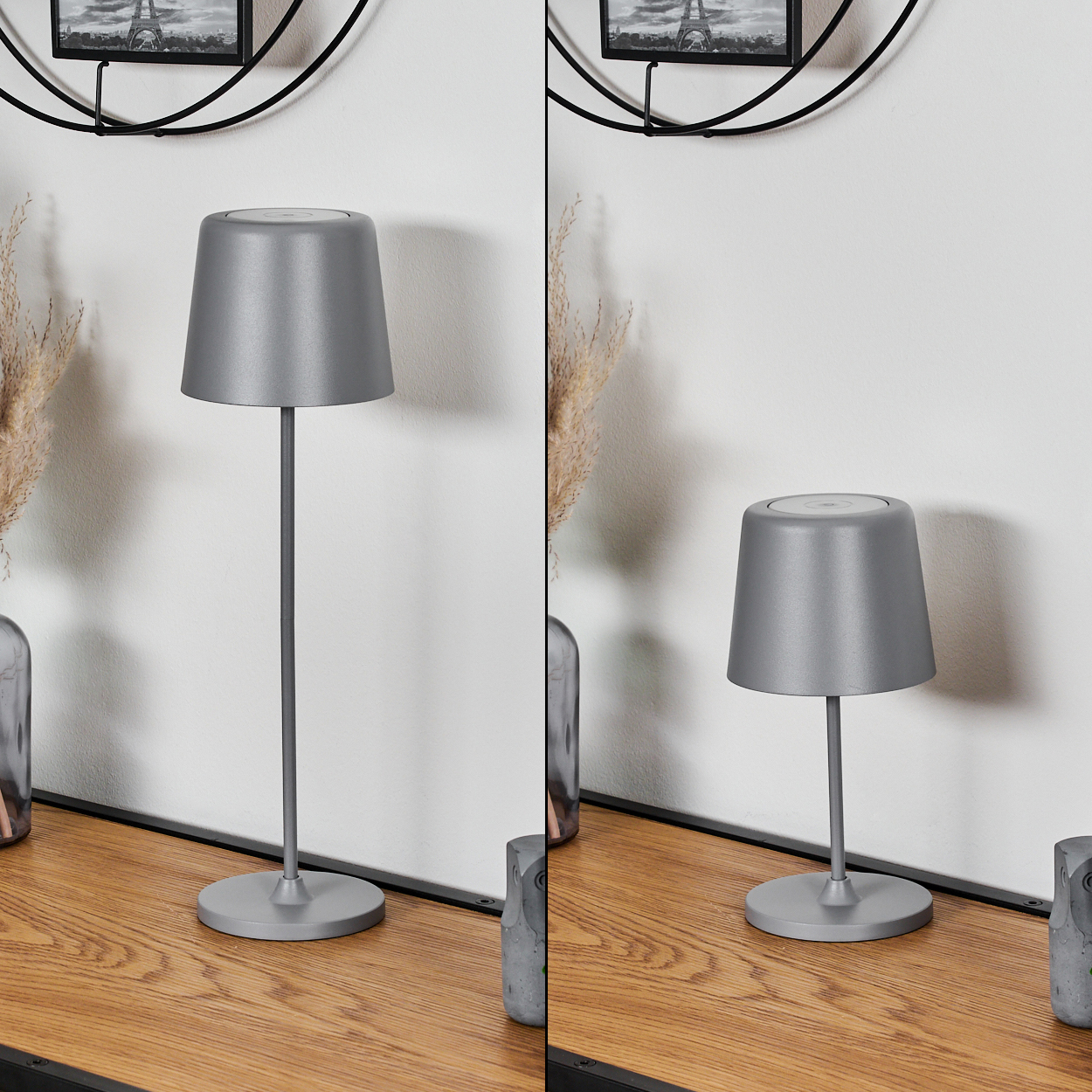 Zwei graue Lampen auf einem Holztisch mit Dekoration und einem schwarz gerahmten Bild im Hintergrund.