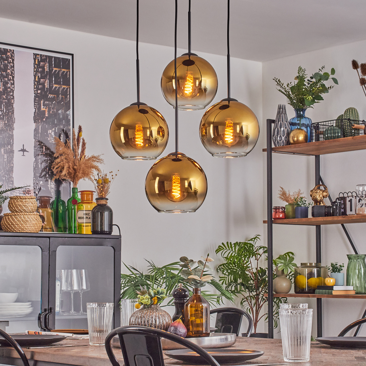 Esszimmer mit goldenen Kugelleuchten, gedecktem Tisch, Pflanzen und Regalen mit Dekoration.