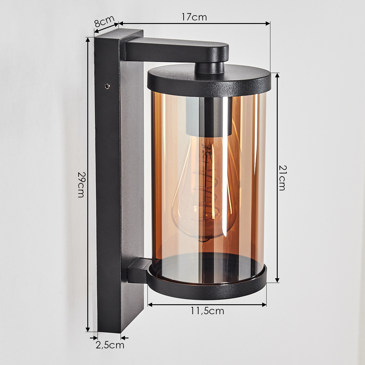 Schwarze Wandlampe mit bernsteinfarbenem Glas, Abmessungen beschriftet. Die Lampe ist an einer weißen Wand montiert. Klare Sicht auf die Glühbirne.