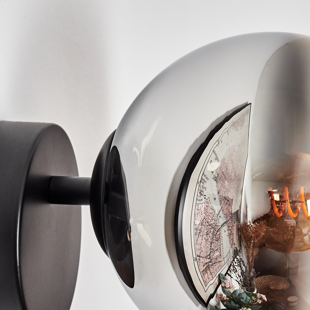 Eine moderne Lampe mit einer Karte im Inneren. Die Lampe hat einen schwarzen Sockel und einen runden, reflektierenden Glasschirm. Im Inneren ist eine Karte zu sehen.