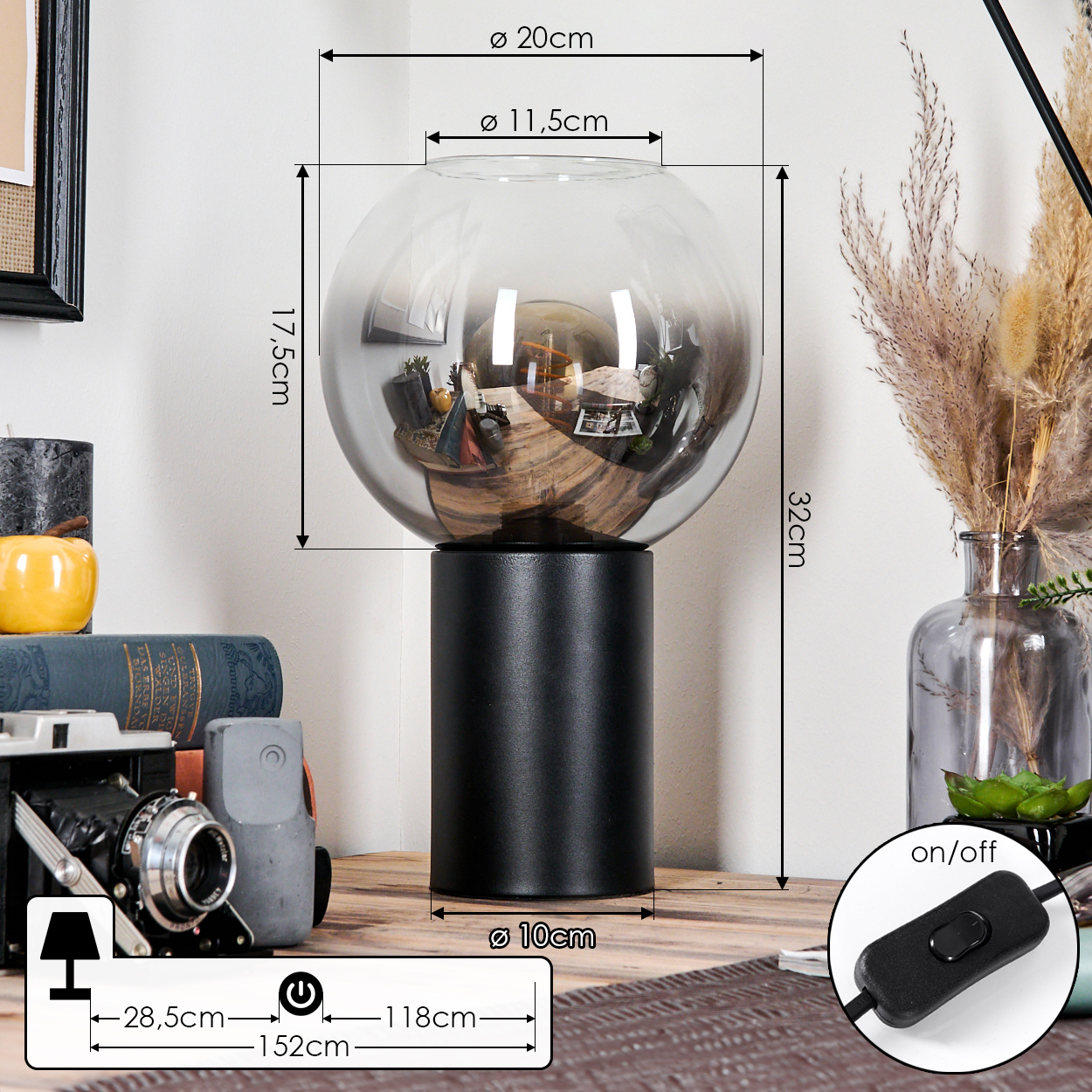 Eine dekorative Lampe mit schwarzem Sockel und Glaskugel. Abmessungen sind angegeben. Weitere Gegenstände sind Kamera und Trockenpflanzen.