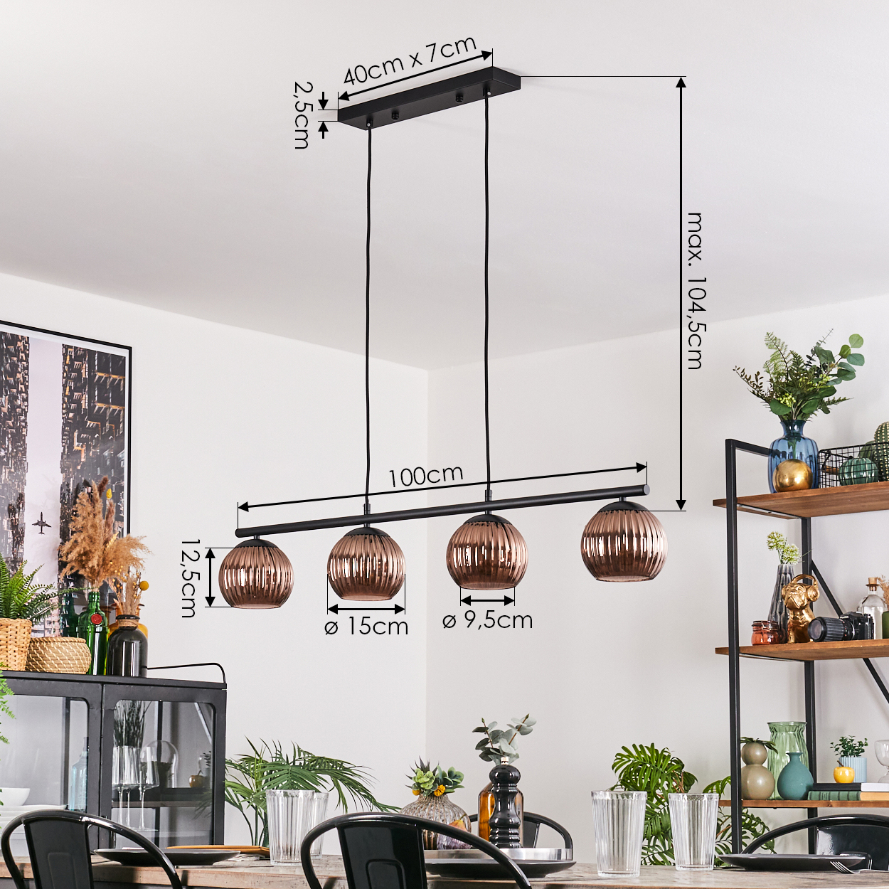Eine moderne schwarze Pendelleuchte mit vier kupferfarbenen Glaslampen hängt über einem Holztisch. Der Hintergrund zeigt Regale und Dekoration.