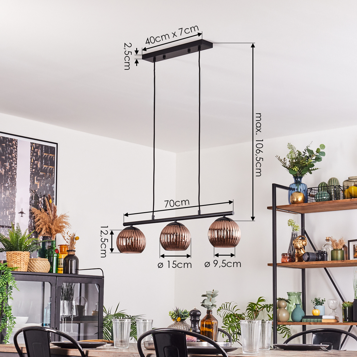 Eine moderne Lampe mit drei kupferfarbenen Glasschirmen hängt über einem Tisch. Im Hintergrund befindet sich ein Regal mit Dekoration und Pflanzen.