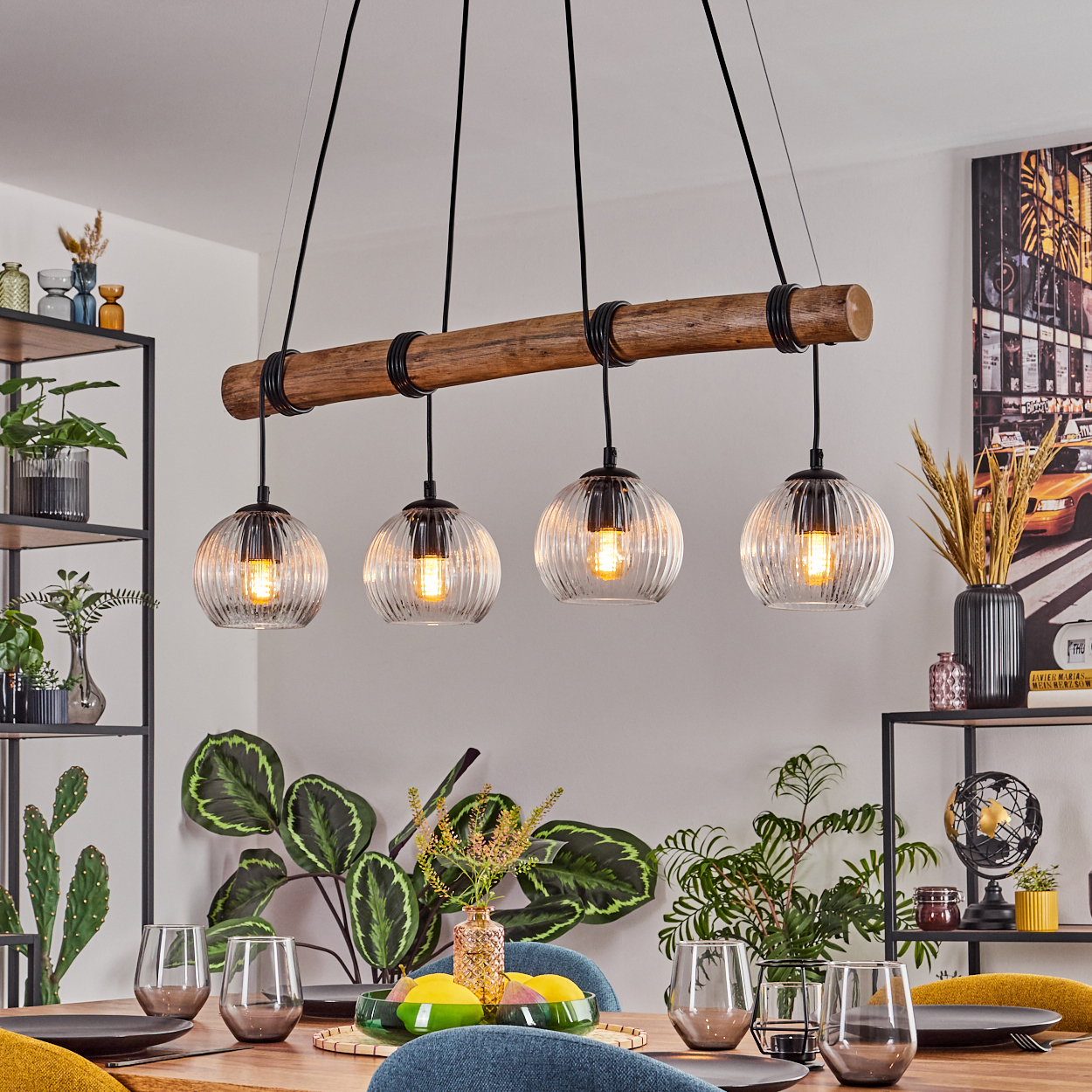 Esszimmer mit Holztisch, Gläsern, Pflanzen und einer Leuchte mit vier Glaskugeln.