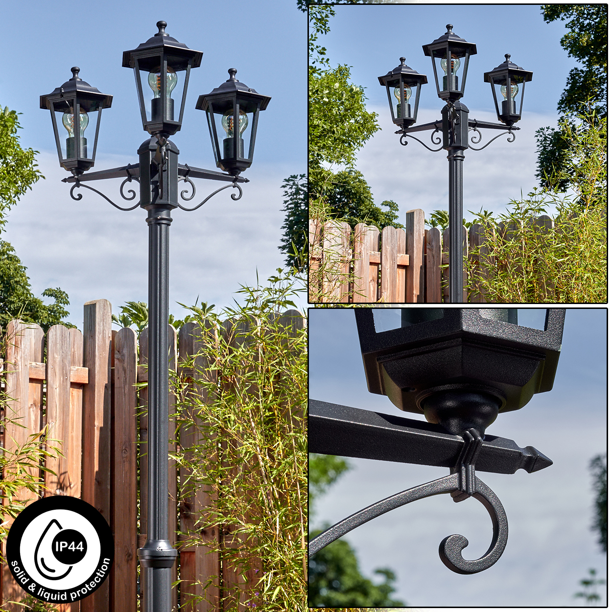 Eine schwarze Laterne mit drei Lampen, vor einem Holzzaun und grünen Pflanzen, mit blauem Himmel im Hintergrund.