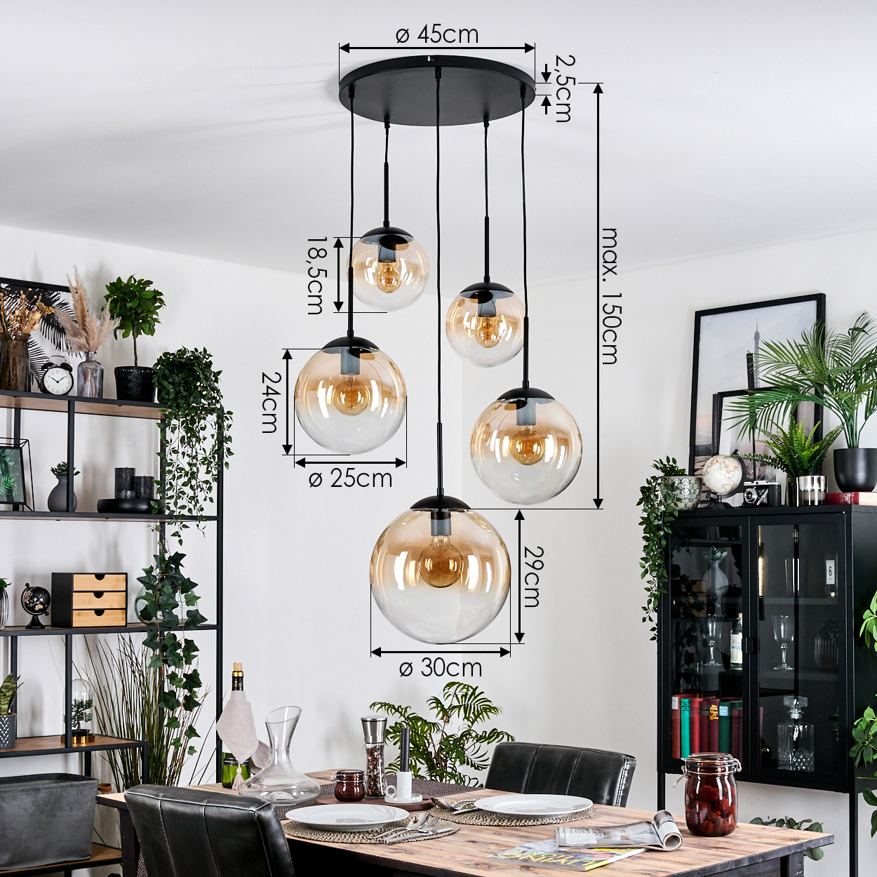 Ein Esszimmer mit einem schwarzen Kronleuchter mit fünf kugelförmigen Lichtern. Ein Esstisch ist mit Tellern und Gläsern gedeckt. Pflanzen und Möbel sind sichtbar.