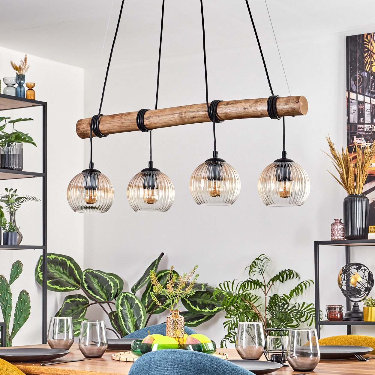 Esszimmer mit Holztisch, Pflanzen und einer Leuchte mit vier Glaskugeln.