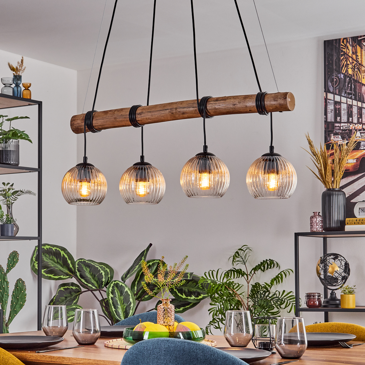 Esszimmer mit Holztisch, Hängelampen, Pflanzen und einem Stadtbildgemälde. Gläser und Teller sind gedeckt.