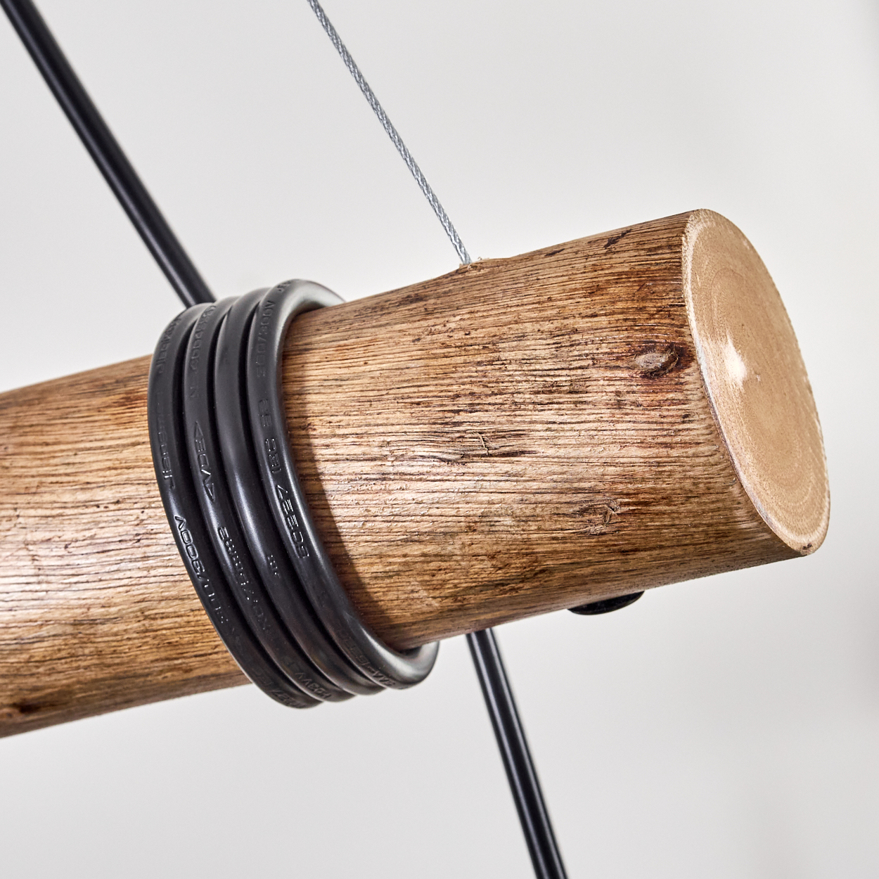 Ein Holzstamm mit schwarzen Kabeln. Ein silbernes Kabel und schwarze Stangen sind ebenfalls vor weißem Hintergrund zu sehen.