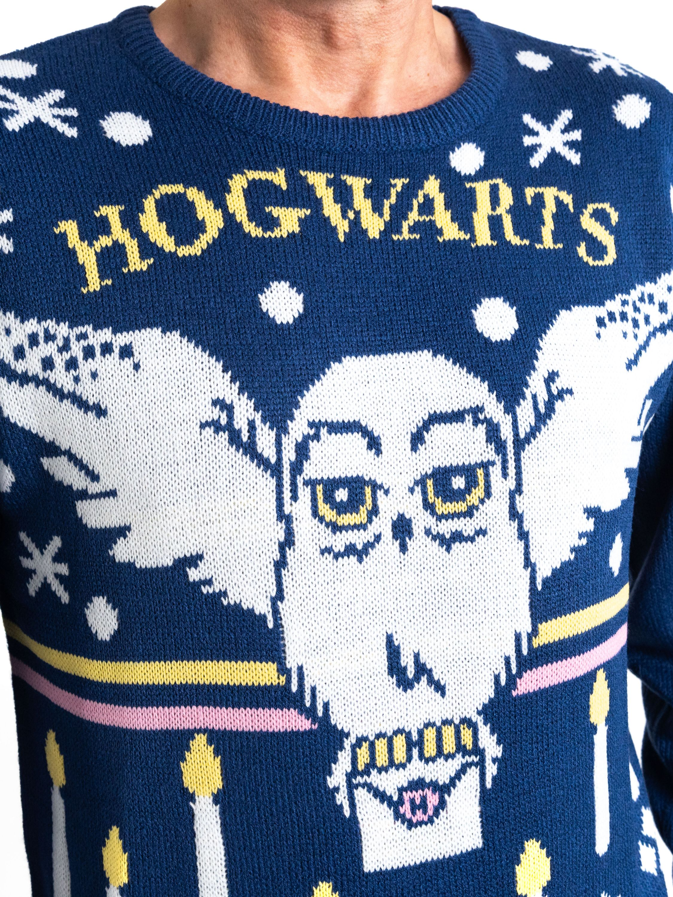 Dunkelblauer Strickpullover mit 'HOGWARTS' und Eulenmuster. Weiße Schneeflocken und Kerzen sind ebenfalls vorhanden.