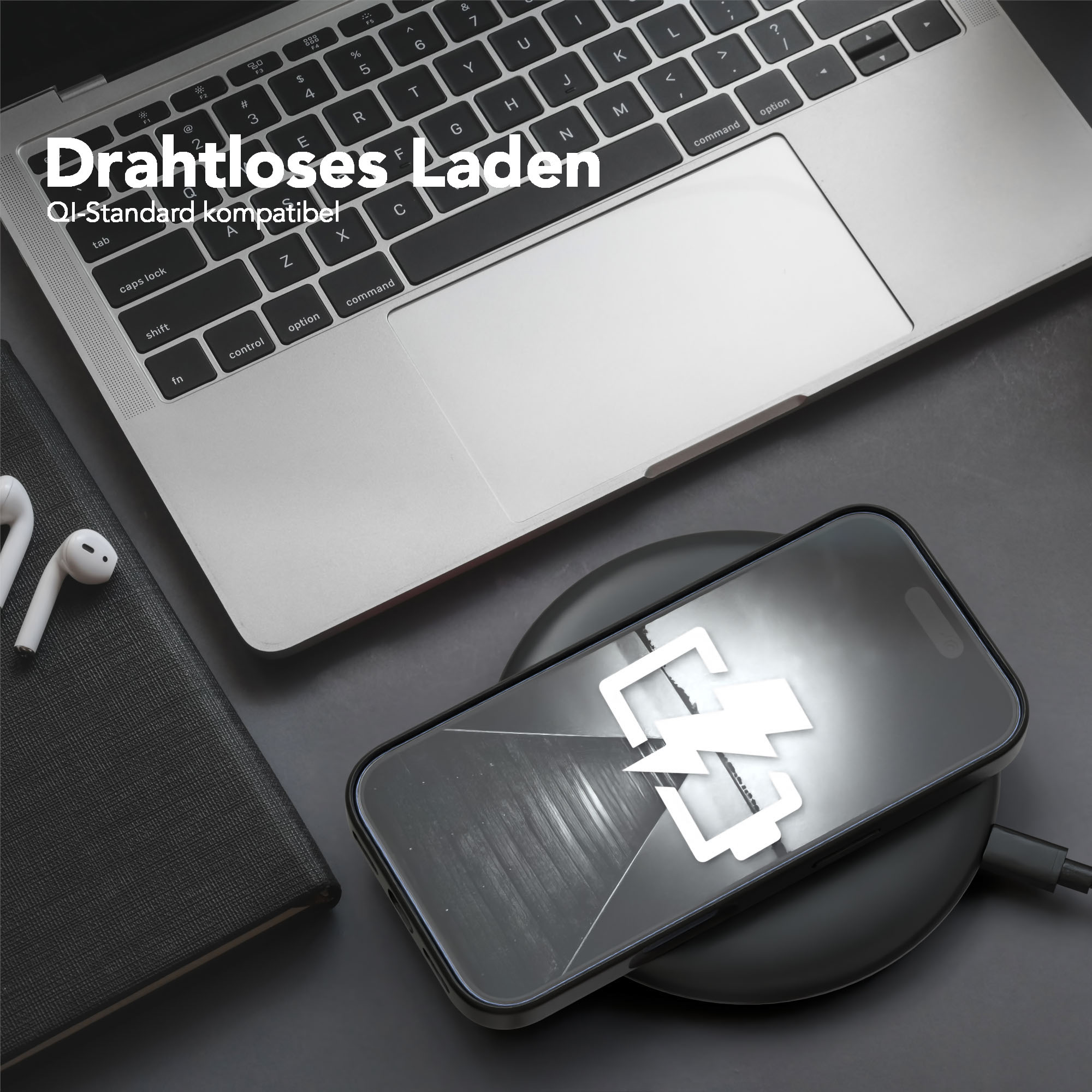 Ein Telefon, das drahtlos auf einem Pad geladen wird, neben einem Laptop und Ohrhörern. Das Telefon zeigt ein Ladesymbol an.