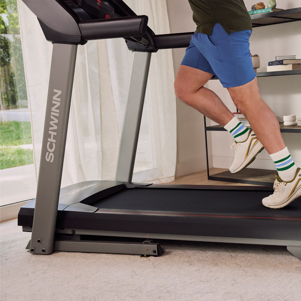 A person runs on a treadmill. They wear blue shorts, white socks with stripes, and white shoes. The treadmill is gray.