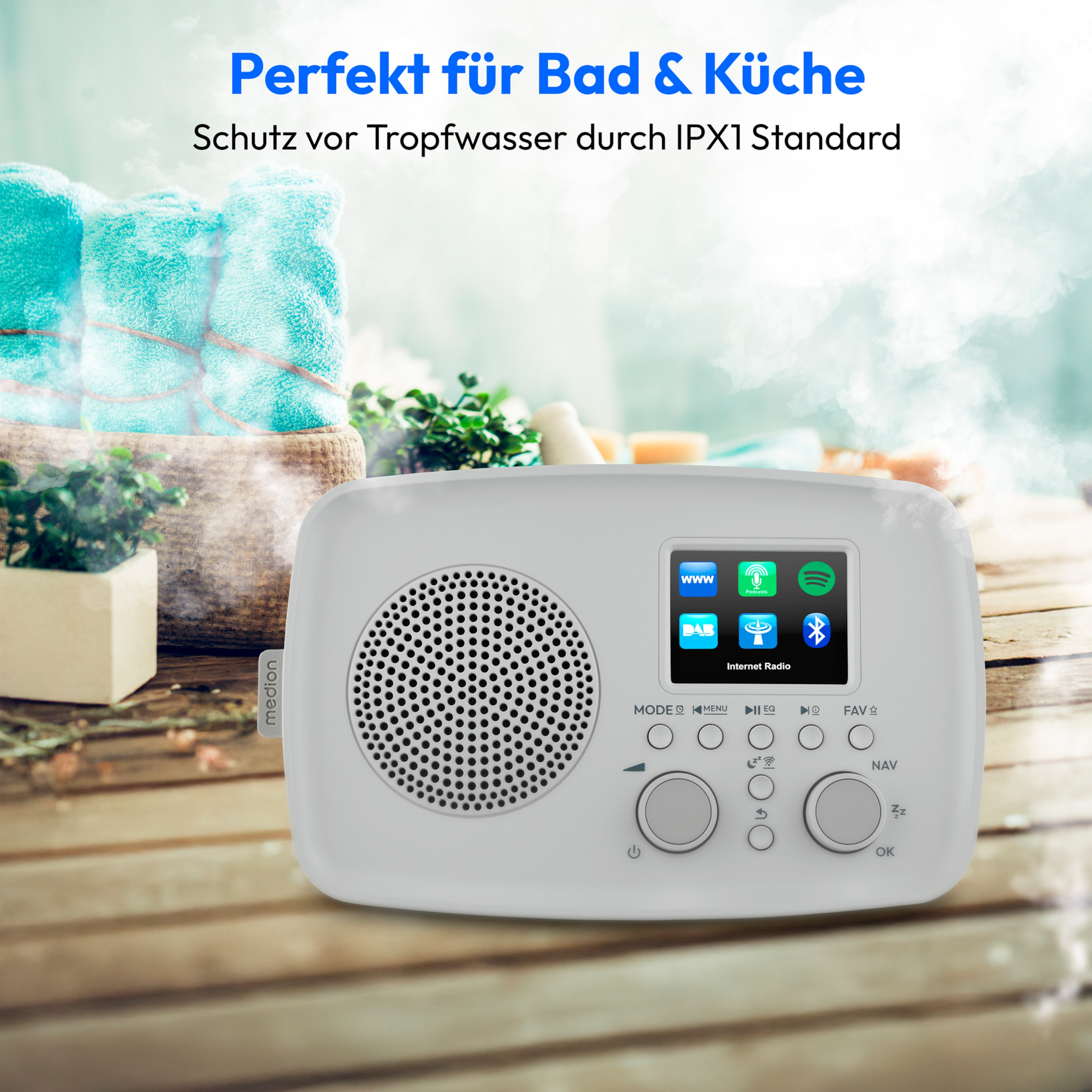A white radio with a screen displaying icons. Turquoise towels and plants are in the background.