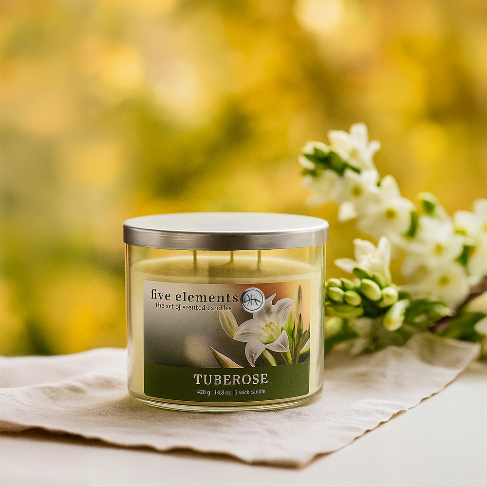 Eine Tuberose-Duftkerze in einem Glas mit weißen Blüten im Hintergrund. Sie steht auf einem beigen Tuch.